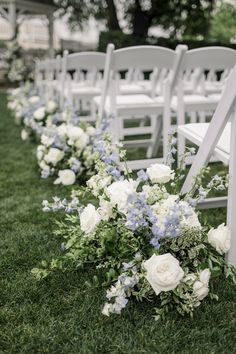 rows of white chairs with blue and white flowers on the grass in front of them