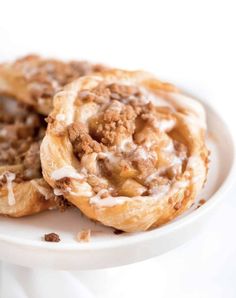 two cinnamon rolls sitting on top of a white plate