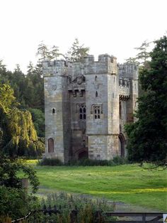 an old castle sitting in the middle of a lush green field with lots of trees