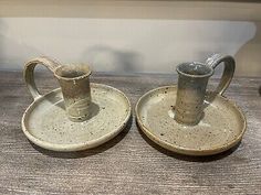 two ceramic cups and saucers sitting on top of a wooden table