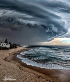 a large storm is coming over the ocean and houses on the beach near the water