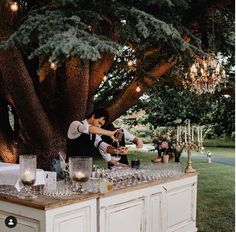 a man and woman standing next to each other at a table with wine glasses on it