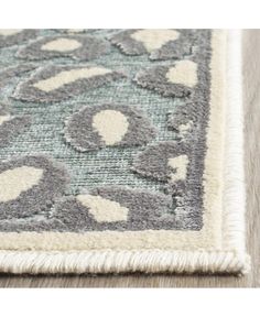 an area rug with grey and white designs on the top, along with a light wood floor