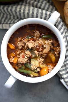 a close up of a bowl of soup with meat and vegetables in it on a towel