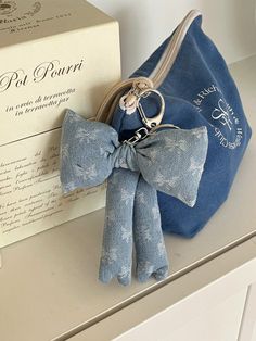 a blue bag with a bow on it next to a box and keychain