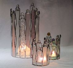 three glass vases with candles in them on a white surface