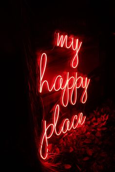 a red neon sign that says my happy place on it's side in the dark