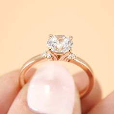 a woman's hand holding an engagement ring with a diamond in the center and two diamonds on each side