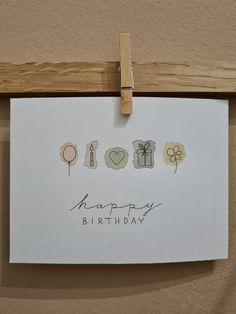 a happy birthday card hanging on a clothes peg with some stickers attached to it