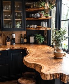 a kitchen with black cabinets and wooden counter tops, along with plants on the shelves