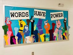 there is a painting on the wall that says words have power and people are holding up signs