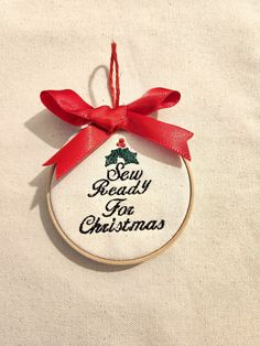 a cross stitch ornament with a red ribbon hanging from it's center