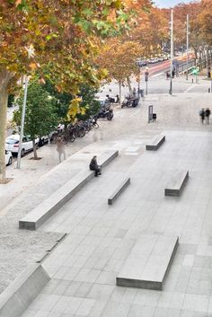 people are sitting and walking on the concrete steps in an open area next to trees