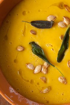 a close up of a bowl of soup with nuts on the top and green garnish