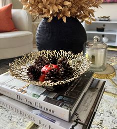 a table topped with books and a bowl filled with pine cones on top of it