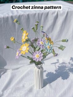 a white vase filled with yellow and purple flowers