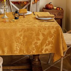 a dining room table with an orange and gold table cloth on it, surrounded by fall decorations