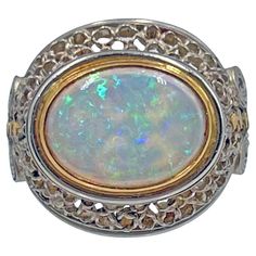 Handmade opal ring in platinum and 18k yellow gold by New York jewelry designer Judy Geib. Central cabochon cut 12 x 9mm pinfire opal, horizontally set in an 18 karat yellow gold bezel. The opal has a vibrant green, blue, and orange play of color. Platinum open-work scroll design surrounds the opal, with a matching open-work band having geometric gold dotted centers. Unsigned. Originally sold by Greenleaf & Crosby in 2015. Finger size 6. Judy Geib, is a NYC based designer who creates hand made pieces with a Bohemian elegance. Her pieces are uniquely one of a kind and usually takes form as it’s made, rather than being designed in advance. Judy Geib, Yellow Gold Opal Ring, Gold Opal Ring, New York Jewelry, Gold Vans, Australian Black Opal, Trio Ring, Carnelian Ring, Opal Ring Gold