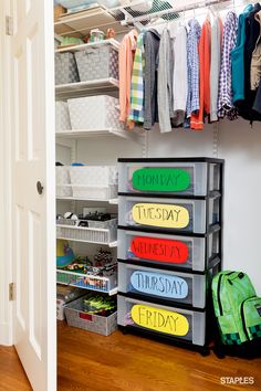 an organized closet with clothes hanging on the wall and plastic bins filled with personal items