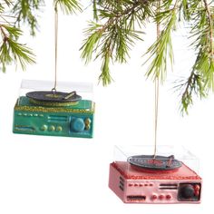 two ornaments hanging from a christmas tree, one with a record player and the other with a radio