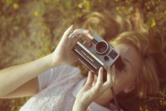 a woman laying on the ground holding up a camera