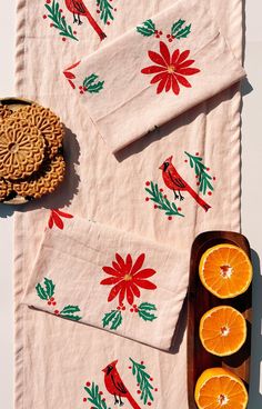 oranges and cookies are laid out on a table with napkins that have red birds on them