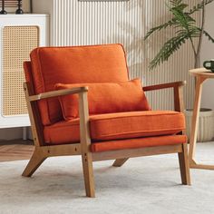 an orange chair sitting on top of a white rug next to a table with a potted plant