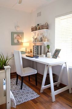 a white desk and chair in a room with wood floors, windows, and pictures on the wall