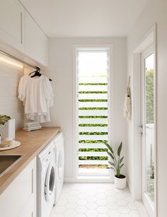 a washer and dryer in a white laundry room next to an open window