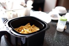 french fries are in a black container on the counter