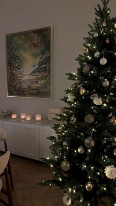 a decorated christmas tree in the corner of a living room with candles on the table