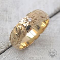 a close up of a gold ring with a flower on the center and diamond in the middle