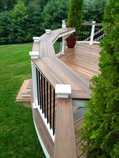 a wooden deck with railings and planters on the top, surrounded by green grass