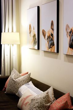 three pictures hang on the wall above a couch with two pillows and a lamp next to it