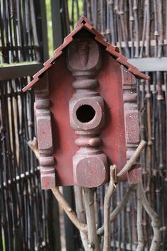 a red birdhouse sitting on top of a tree branch