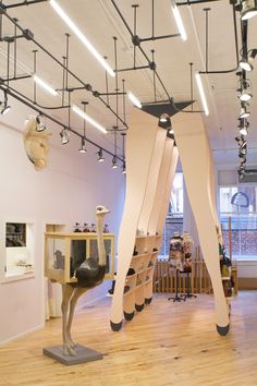 an art gallery with wooden floors and sculptures on the walls, suspended from ceiling lights