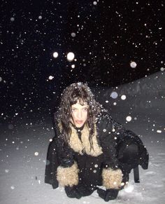 a woman kneeling down in the snow with her teddy bear on her lap and eyes closed