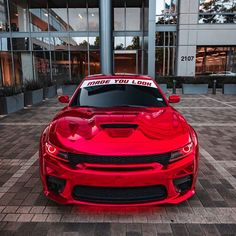 a red sports car with a thank you look on it's hood is parked in front of a building