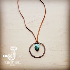 a necklace with a turquoise stone in the center on a brown cord that is hanging from it