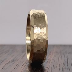 a gold wedding ring on top of a wooden table