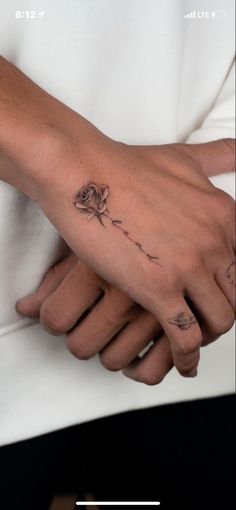 a woman's hand with a rose tattoo on her left wrist and the other arm