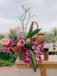 a basket filled with pink flowers sitting on top of a table next to an umbrella