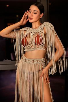 a woman in a fringed outfit poses for the camera