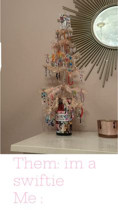 there is a small white christmas tree on the table in front of a wall mirror