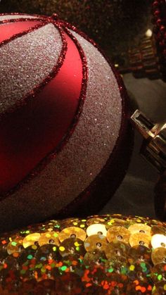 a close up of two christmas ornaments with glitter on the bottom and one red ornament in the middle