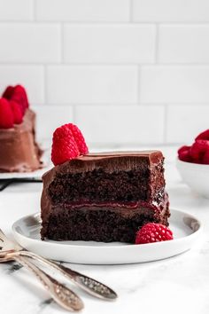 a slice of chocolate cake on a plate with raspberries next to the rest