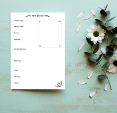 a blank notepad with flowers and leaves on a blue surface next to the paper