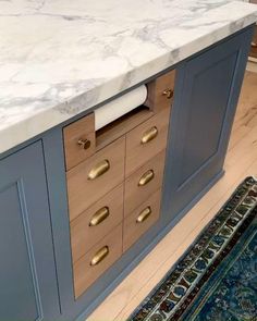 a marble counter top in a kitchen with gold pulls on the cabinet doors and drawers