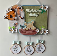 a welcome baby sign hanging from the side of a wall next to three magnets