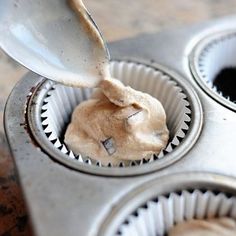 a cupcake tin filled with batter being poured into the muffins in it